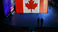 Workers stand under a blue glow and the Canadian flag at the Tribute Communities Centre, where the leader of the Conservative Party of Canada, Erin O'Toole, is expected to speak at an election night event in Oshawa, Ontario, Canada, on Monday, Sept. 20, 2021. Canadian Prime Minister Justin Trudeau is poised to win a third term in a snap election but fall short of regaining the parliamentary majority he was seeking. Photographer: Cole Burston/Bloomberg