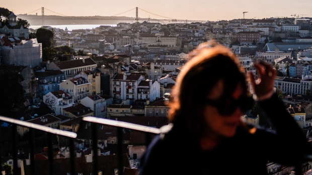 Tourists look out towards residential and commercial buildings on the skyline from a terrace at Miradouro da Graca in Lisbon, Portugal, on Friday, Nov. 8, 2019. While Spain's debt has been seen as safer than neighboring Portugal's since the financial crisis, yields have recently climbed above those on their Mediterranean peer.