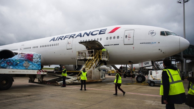 Workers prepare cargo for loading on a Boeing Co 777-300ER passenger plane, operated by Air France-KLM, before departure to Los Angeles, U.S., at Charles de Gaulle airport in Roissy, France, on Monday, May 10, 2021. European Union leaders urged U.S. President Joe Biden to lift restrictions on exports of Covid-19 vaccines to address the desperate needs of developing countries before embarking on complex discussions about whether patent waivers might also boost supply in the longer term. Photographer: Nathan Laine/Bloomberg