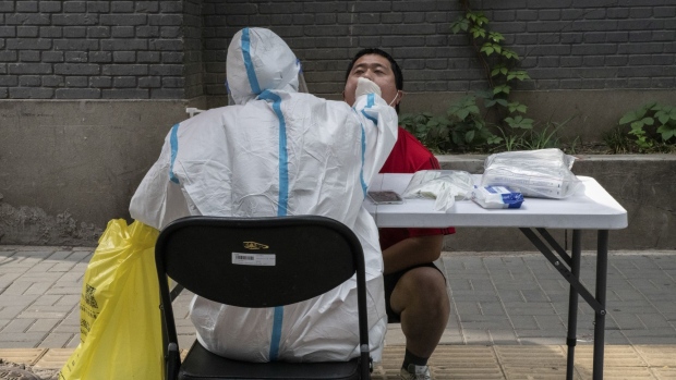 A healthcare worker wearing personal protective equipment (PPE) collects a swab sample from a resident at a Covid-19 testing facility in Beijing China, on Monday, May 23, 2022. Beijing reported a record number of Covid cases during its current outbreak, reviving concern the capital may face a lockdown as authorities seek to stamp out community spread of the virus.