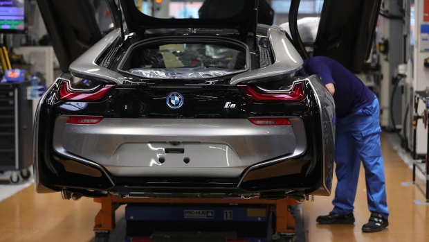 An employee secures a dihedral door frame fitting on a BMW i8 hybrid electrical automobile at the Bayerische Motoren Werke AG factory in Leipzig, Germany in 2019.