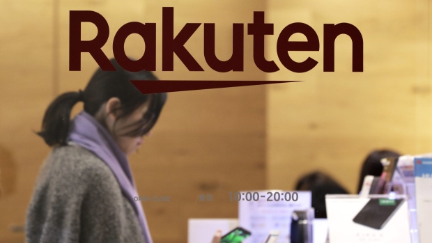 The Rakuten Inc. logo is displayed on a glass door while a customer looks at a smartphone inside the company's cafe in Tokyo, Japan, on Monday, Jan. 28, 2019. Rakuten's chief executive officer Hiroshi Mikitani says the company is aiming to lower prices in Japan's wireless market. Photographer: Kiyoshi Ota/Bloomberg