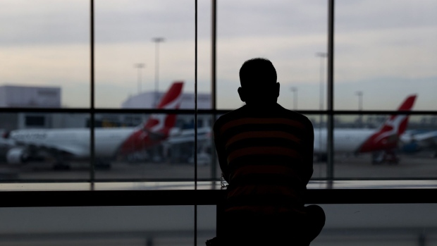A traveler looks at aircraft operated by Qantas Airways Ltd. docked at gates at the international terminal of Sydney Airport in Sydney, Australia, on Monday, Nov. 1, 2021. Vaccinated overseas travelers entering Australia's biggest states, New South Wales and Victoria, no longer need to quarantine on arrival, while millions of Australians living on the country’s east coast can finally leave their home soil without a permit.