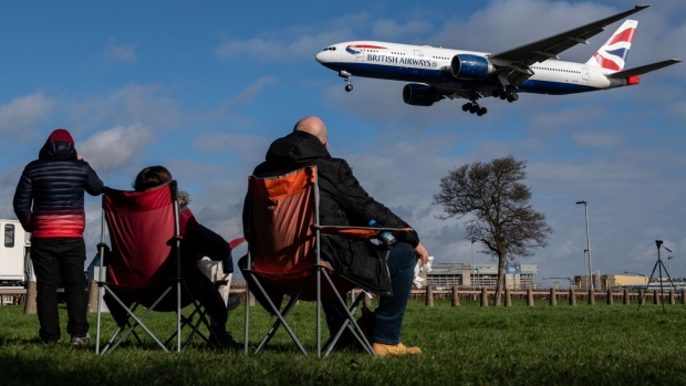 Plane spotters watch a passenger airplane, operated by British Airways, a unit of International Consolidated Airlines Group SA (IAG), coming in to land at London Heathrow Airport in London, U.K., on Wednesday, Feb. 23, 2022. IAG are due to report results on Friday. Photographer: Chris J. Ratcliffe/Bloomberg