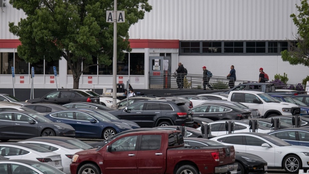 People enter the Tesla Inc. assembly plant in Fremont, California, U.S., on Monday, May 11, 2020. Elon Musk restarted production at Tesla's only U.S. car plant, flouting county officials who ordered the company to stay closed and openly acknowledging he was risking arrest for himself and his employees.