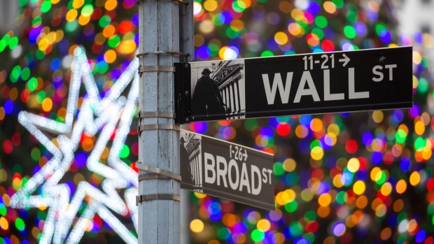 A Wall Street street sign in front of the New York Stock Exchange (NYSE) in New York, U.S., on Friday, Dec. 31, 2021. U.S. stocks swung between gains and losses, with moves exacerbated by thin trading on the last session of the year. Photographer: Michael Nagle/Bloomberg