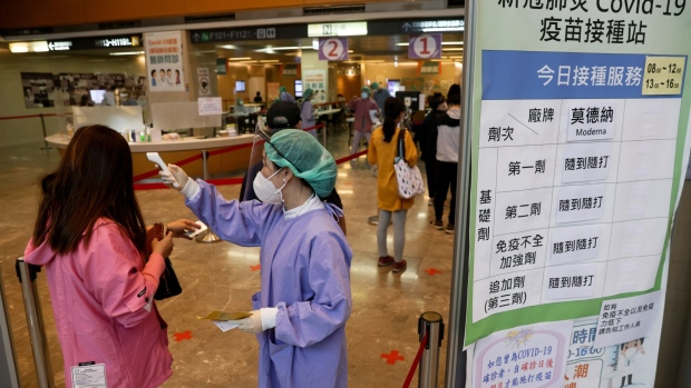 A medical staff checks the temperature of a resident at an entrance to a Covid-19 vaccination center at the Far Eastern Memorial Hospital in New Taipei City, Taiwan, on Monday, May 23, 2022. Lending weight to a gradual shift to living with Covid is the fact that 99% of cases in Taiwan this year have been mild or asymptomatic, according to Taiwan Centers for Disease Control.