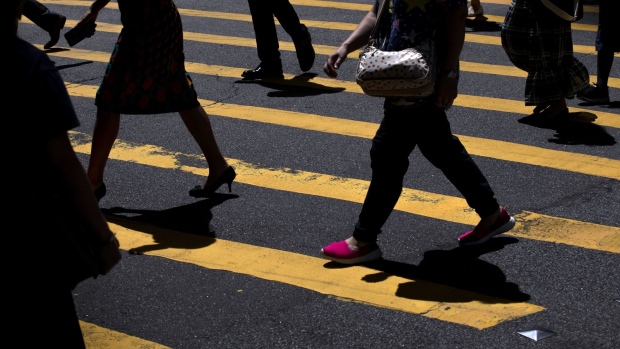 People cross a road during lunch hour in Central district in Hong Kong, China, on Wednesday, Aug. 18, 2021. Hong Kong is caught between its desire to reopen and the government's zero tolerance for any cases of Covid-19, which has kept the virus out for most of the pandemic. Photographer: Paul Yeung/Bloomberg