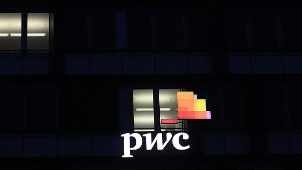 A logo sits illuminated on the offices of Pricewaterhouse Coopers International Ltd. (PwC) in Stuttgart, Germany. Photographer: Krisztian Bocsi/Bloomberg