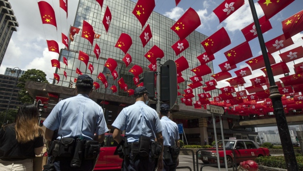 Police officers stand under the flags of China and Hong Kong Special Administrative Region (HKSAR) hanging from buildings during the anniversary of Hong Kong's return to Chinese in Hong Kong, China, on Thursday, July 1, 2021. Hong Kong's leader pledged to press ahead with an unprecedented national security crackdown, as the Asian financial center marked a series of fraught anniversaries symbolizing Beijing’s tightening grip over local affairs. Photographer: Paul Yeung/Bloomberg
