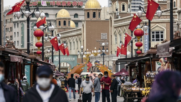 Pedestrians wearing protective masks walk past stalls at the Xinjiang International Grand Bazaar in Urumqi, Xinjiang province, China, on Wednesday, May 12, 2021.  Source: Bloomberg