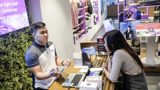 An employee, left, assists a customer at a service desk at a Globe Telecom Inc. Iconic store in Manila, the Philippines, on Monday, Oct. 23, 2017. Globe is tapping its partnership with Chinese Billionaire Jack Ma’s Ant Financial for capital, expertise and technology, Cu said in an interview.