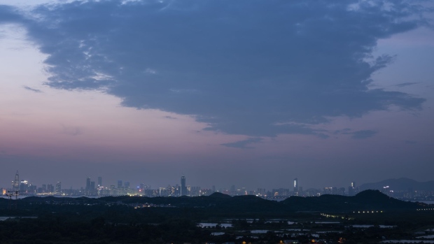 Illuminated buildings in Shenzhen stand on the horizon beyond residential buildings and farmland at night in the Yuen Long district of Hong Kong, China, on Monday, Sept. 9, 2019. Hong Kong's waning allure for ambitious mainland Chinese is symbolic of the shifting balance of power and opportunities between the city and its neighbour Shenzhen. Where Hong Kong is a former colony whose historic role as a trading hub and gateway to China is fading, Shenzhen is young, hopeful and looks optimistically toward a future where it can help drive China’s push to dominate the next century through an innovative economy that sidesteps political freedoms. Photographer: Justin Chin/Bloomberg