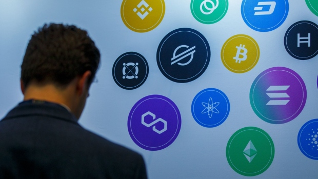 An attendee near logos of different cryptocurrencies at the CryptoCompare Digital Asset Summit at Old Billingsgate in London, U.K., on Wednesday, March 30, 2022. Bitcoin and other cryptocurrencies had been, up until the last few weeks, mired in a similar downtrend as other riskier assets, like U.S. stocks. Photographer: Luke MacGregor/Bloomberg