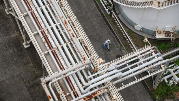 A worker walks under pipelines at Jera Co.'s liquefied natural gas (LNG) fired power plant inside the company's Anegasaki Thurmal Power Station in Ichihara, Chiba Prefecture, Japan, on Wednesday, June 22, 2022. Jera, a joint venture between Tokyo Electric Power Co. (Tepco) and Chubu Electric Power Co., won the bid in a public auction to supply additional power during this summer. Homes and businesses are being asked to conserve electricity to help avoid blackouts during a squeeze on global energy supplies. Photographer: Akio Kon/Bloomberg