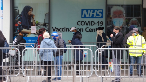 Visitors queue for Covid-19 vaccinations at a National Health Service (NHS) walk-in vaccine center at Romford, U.K., on Monday, Dec. 13, 2021. Prime Minister Boris Johnson warned the U.K. is facing a "tidal wave" of omicron infections and set an end-of-year deadline for the country’s booster vaccination program. Photographer: Chris Ratcliffe/Bloomberg
