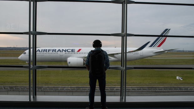A passenger looks out from the gate towards an aircraft as it taxis to the runway at Paris Charles de Gaulle airport in Paris, France, on Friday, Oct. 29, 2021. Air France-KLM expects a return to profitability for the full year and is adding transatlantic seats as an easing of travel rules revives prospects for the struggling carrier.