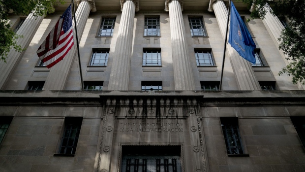 An American flag flies outside the Department of Justice building in Washington, D.C., U.S., on Monday, June 21, 2021. The White House plan for trillions of dollars in proposed spending and tax increases is entering a procedural and political thicket in Congress that's likely to take at least until September to clear.