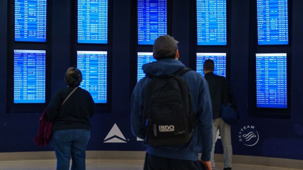 Travelers view the arrival and departure boards at the Hartsfield-Jackson Atlanta International Airport (ATL) in Atlanta, Georgia, U.S., on Tuesday, Dec. 21, 2021. Airline passenger numbers in the U.S. totaled 2.12 million on Dec. 19, compared with 1.06 million the same weekday a year earlier, according to the Transportation Security Administration. Photographer: Elijah Nouvelage/Bloomberg