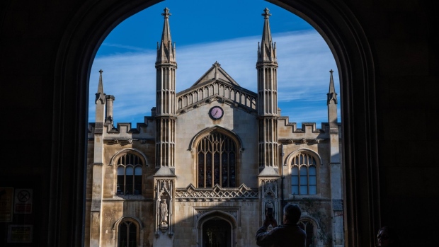 A tourist takes a photograph of Corpus Christi College, part of the University of Cambridge. Photographer: Chris J. Ratcliffe/Bloomberg