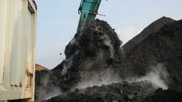 An excavator loads coal onto a dump truck at Cirebon Port in West Java, Indonesia. Photographer: Dimas Ardian/Bloomberg