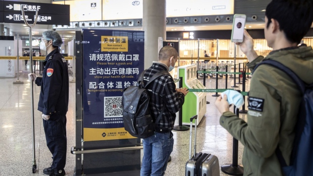 Travelers in front of a sign indicating various Covid-19 measures at the Hongqiao International Airport in Shanghai, China, on Monday, March 21, 2022. More than 100 international flights were diverted away from Shanghai to other cities to ease pressure on quarantine hotels and isolation facilities in the financial hub as China battles growing pockets of Covid-19. Photographer: Qilai Shen/Bloomberg