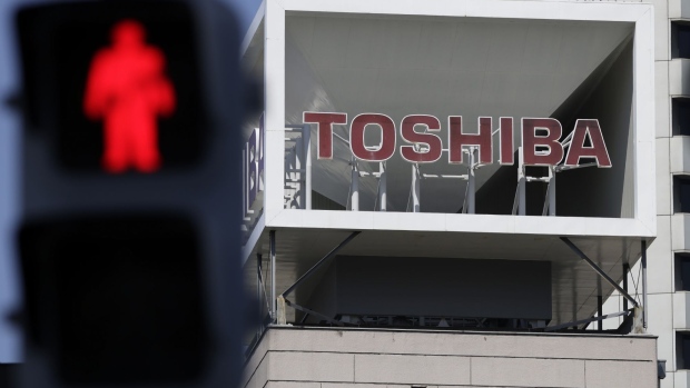 Signage for Toshiba Corp. displayed at the company's headquarters while the red figure is illuminated on a pedestrian light in Tokyo, Japan, on Wednesday, April 7, 2021. Toshiba surged its daily limit of 18% after confirming it received an initial buyout offer from CVC Capital Partners, setting the stage for potentially the largest private equity-led acquisition in years. Photographer: Kiyoshi Ota/Bloomberg