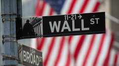 A Wall Street street sign in front of the New York Stock Exchange (NYSE) in New York, U.S., on Friday, Dec. 31, 2021. U.S. stocks swung between gains and losses, with moves exacerbated by thin trading on the last session of the year.