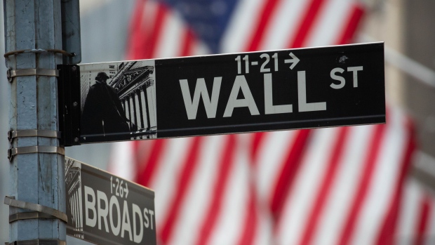 A Wall Street street sign in front of the New York Stock Exchange (NYSE) in New York, U.S., on Friday, Dec. 31, 2021. U.S. stocks swung between gains and losses, with moves exacerbated by thin trading on the last session of the year.