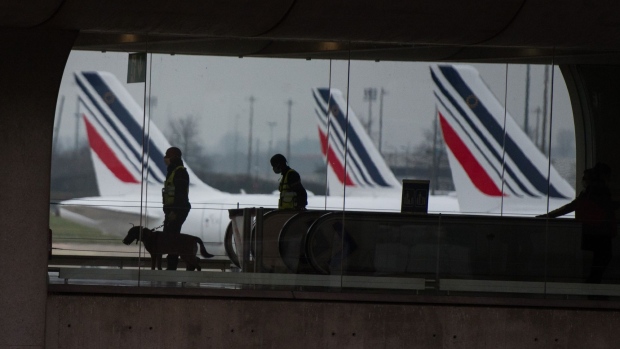 French police officers and a sniffer dog patrol a terminal building at Paris-Charles de Gaulle airport in Paris, France, on Tuesday, Dec. 14, 2021. The omicron variant of Covid-19 is scrambling the European Union’s plans to simplify its travel rules, particularly as some countries move ahead with new unilateral restrictions.