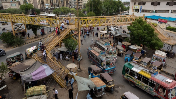 People cross over a pedestrian bridge under a traffic junction in Karachi, Pakistan, on Thursday, June 30, 2022. Pakistani government has increased gasoline prices by 14.83 rupees/liter to 248.74 rupees/liter effective July 1, the Pakistan Finance Ministery said in a statement. The levy imposed as one of prior actions set by the International Monetary Fund to to revive its loan program, Pakistan Finance Minister Miftah Ismail says at news conference. IMF to extend its bailout program to four years and enhance its funding by $1b to $7b.