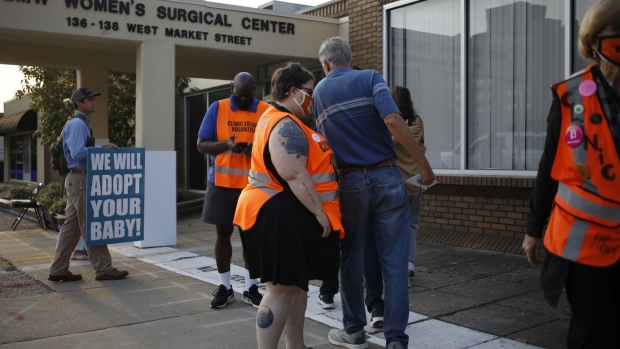 Volunteer clinic escorts wait near demonstrators outside the EMW Women's Surgical Center in Louisville, Kentucky, U.S., on Tuesday, Sept. 28, 2021. The EMW Women's Surgical Center is now part of a U.S. Supreme Court term that could gut the constitutional right to abortion and allow sweeping new restrictions in much of the country.