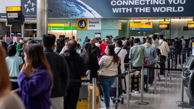 Passengers queue to check in inside the arrivals hall of Terminal 2 at London Heathrow Airport in London, U.K., on Wednesday, April 13, 2022. Travel disruption continued to hit U.K. holidaymakers as officials warned of expected queues at airports later in the week and motorists faced fuel shortages.