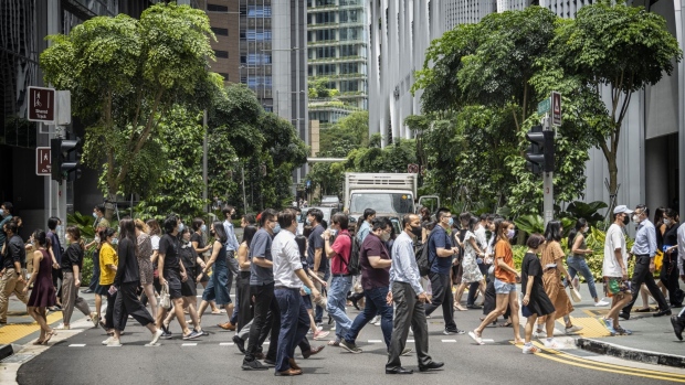 Pedestrians in the central business district in Singapore, on Tuesday, April 26, 2022. Singapore began allowing all workers to return to the workplace and doing away with checking people’s vaccination statuses at most places.