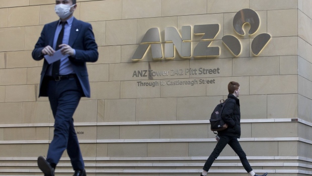 Pedestrians walk past the Australia & New Zealand Banking Group Ltd. (ANZ) logo displayed at the company's building in Sydney, Australia, on Tuesday, Aug. 18, 2020. ANZ Bank will pay shareholders a dividend even as it took further bad-debt provisions to cover the continuing Covid-related economic fallout. Photographer: Brent Lewin/Bloomberg