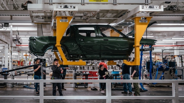 Workers assembly components of a Rivian R1T electric vehicle (EV) pickup truck at the company's manufacturing facility in Normal, Illinois, US., on Monday, April 11, 2022. Rivian Automotive Inc. produced 2,553 vehicles in the first quarter as the maker of plug-in trucks contended with a snarled supply chain and pandemic challenges.