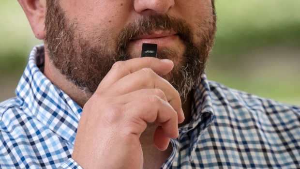 A Juul Labs Inc. e-cigarette and flavored pods are arranged for a photograph in the Brooklyn Borough of New York, U.S., on Sunday July 8, 2018. Juul Labs, the maker of the popular e-cigarette brand that has recently come under fire from health officials over its popularity with young adults, plans to introduce a line of lower-nicotine pods. The company will begin to sell pods with a 3-percent nicotine concentration in its mint and Virginia tobacco flavors later this year, according to a statement Thursday. Photographer: Gabby Jones/Bloomberg