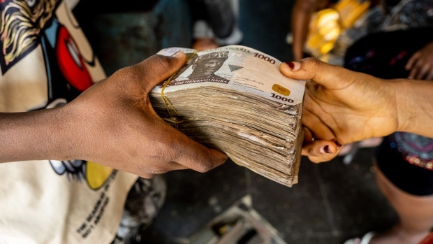 A customer hands over bundles of 1000 Naira banknotes to a trader inside a market in Lagos, Nigeria, on Friday, April 22, 2022. Choked supply chains, partly due to Russia’s invasion of Ukraine, and an almost 100% increase in gasoline prices this year, are placing upward price pressures on Africa’s largest economy. Photographer: Damilola Onafuwa/Bloomberg