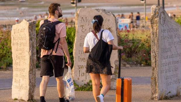 Travellers wheel suitcases along the seafront in Margate, UK, on Friday, June 17, 2022. Experts say office workers being set free offers a rare opportunity to kickstart sluggish economies.