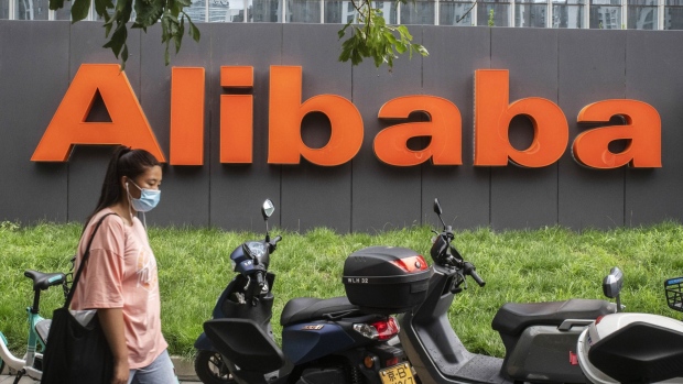A pedestrian wearing a protective mask walks past the Alibaba Group Holding Ltd. logo displayed in front of the company's building in Beijing, China, on Wednesday, Aug. 19, 2020. U.S. President Donald Trump is threatening to slap TikTok-style sanctions on more Chinese companies and Alibaba Group Holding Ltd., as the largest of them all, may be next in line. Photographer: Gilles Sabrie/Bloomberg