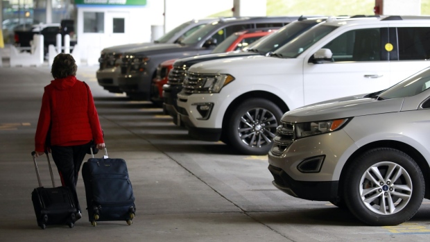 A traveler pulls luggage past a line rental vehicles at a Hertz location at the Louisville International Airport in Louisville, Kentucky, U.S., on Thursday, Jan. 20, 2022. The U.S. car rental industry achieved overall revenues of $28.1 billion in 2021 - a 21% gain over the pandemic year of 2020, according to data collected by Auto Rental News.