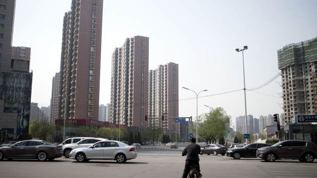 A man riding on an electric bicycle waits at an intersection in front of residential buildings in the Taiyanggong area of Beijing, China, on Monday, April 16, 2018. New home prices in Beijing and Shanghai have jump more than 25 percent over the last two years. Photographer: Giulia Marchi/Bloomberg