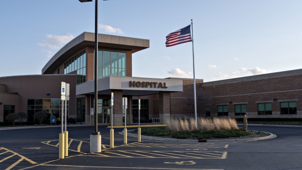 An American flag flies outside OSF Saint Paul Medical Center in Mendota, Illinois, U.S., on Tuesday, April 14, 2020. Hospitals are facing shortages of masks, gowns, gloves, tests, ventilators, cleaning supplies and toilet paper, a federal survey of hospital administrators conducted in late March found.