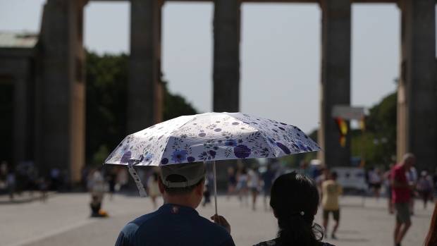 Tourists shelter from the sun under an umbrella near the Brandenburg Gate during a heatwave in Berlin, Germany, on Thursday, July 25, 2019. Europe’s latest summer heatwave broke heat records just weeks after the continent recorded its hottest ever June, fueling concern that a shifting climate is making extreme weather events more frequent.