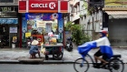 A fruit vendor sits waiting for customers at her cart outside a Circle K store in Ho Chi Minh City, Vietnam.