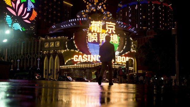 A man walks towards the Casino Lisboa, operated by SJM Holdings Ltd., illuminated at night in Macau. Photographer: Brent Lewin/Bloomberg