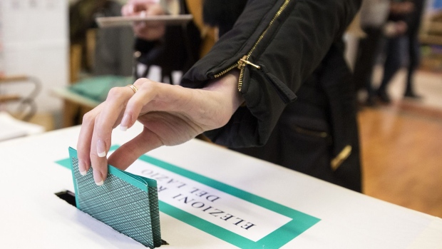 A voter casts her ballot at a polling station during the Italian general election in Rome, Italy, on Sunday, March 4, 2018. Italians are voting Sunday after a campaign that featured the surprise comeback of media magnate and former premier Silvio Berlusconi and a challenge to mainstream parties by the populist Five Star Movement.