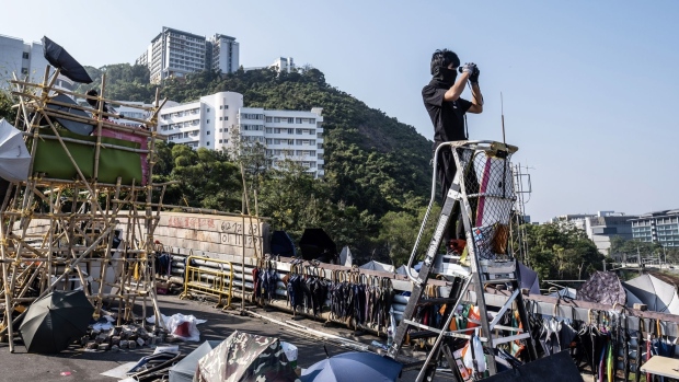 A demonstrator use a pair of binoculars atop a ladder while occupying the No. 2 Bridge during a protest at the Chinese University of Hong Kong (CUHK) in Hong Kong, China, on Friday, Nov. 15, 2019. While Hong Kong's eight government-subsidized universities -- like their counterparts around the world -- have a long history of political activism, the protests gripping Hong Kong for the past five months have brought unprecedented battles onto the campus green. Several campuses have seen extended sieges in recent days as anger flared over the Nov. 8 death of a student who had fallen near police efforts to disperse a protest.