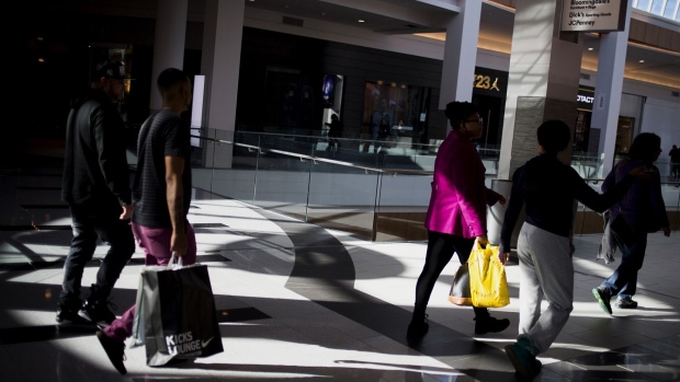 Shoppers carry bags while walking at the Roosevelt Field Mall in Garden City, New York. Photographer: John Taggart/Bloomberg
