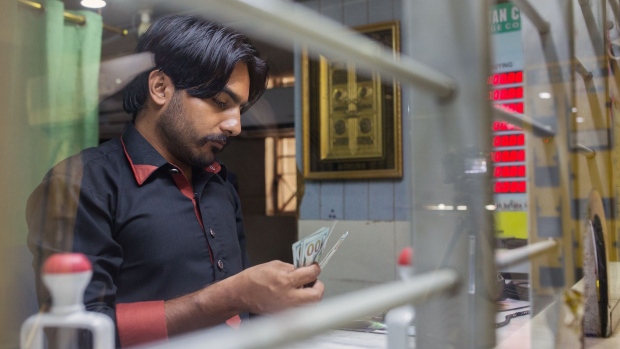 A teller counts U.S. hundred dollar bills inside a currency exchange store in Karachi, Pakistan, on Monday, July 9, 2018. The Pakistan economy is in distress. How else to describe an emerging market that has seen three currency devaluations since December, depleted its foreign-currency reserves and may soon ask for a bailout from the International Monetary Fund, less than two years after its last $6.6 billion emergency cash infusion. Photographer: Asim Hafeez/Bloomberg